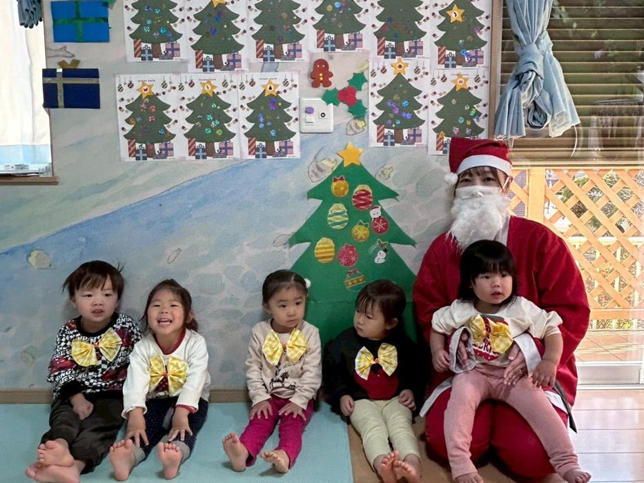 サンタとクリスマス飾りを背景に座る子供たち