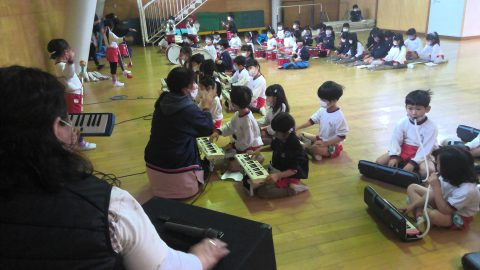 子供たちが鍵盤ハーモニカを演奏する様子。6月【年少々】スタンプ遊び、音楽の授業。幼稚園の教室。