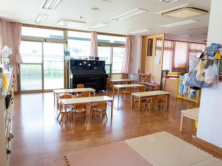ピアノ、机、椅子が並ぶ永福こども園の明るい保育室