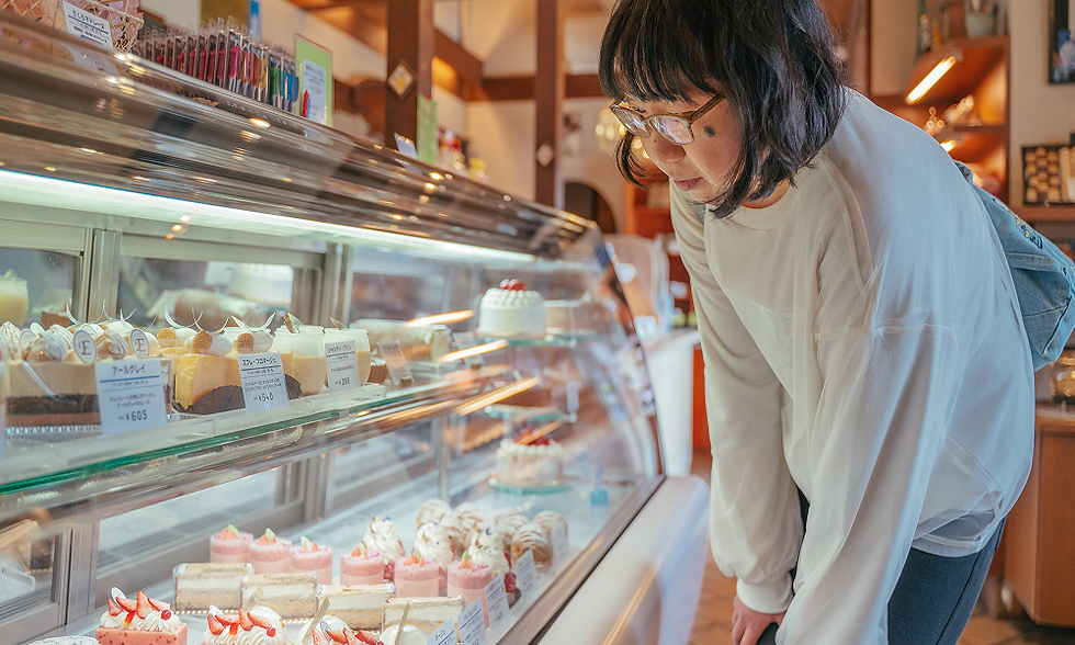 女性がケーキのショーケースを眺めている