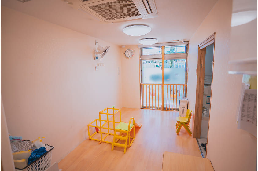 明るい室内、黄色い遊具と椅子。窓から光が差し込む。