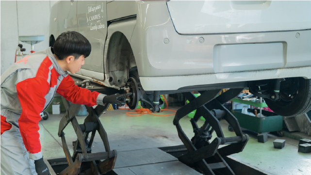 リフトアップされた車の足回りを点検する整備士