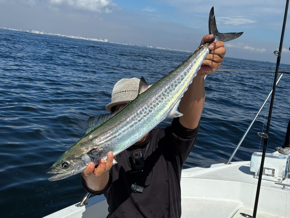 釣り人が釣った魚を見せる、青い海を背景に。遊漁船(ゆみと丸)