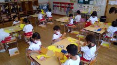 保育園の子供達が工作中。白いマスク姿、机に向かい制作活動中です。7月【年少々】今週の様子