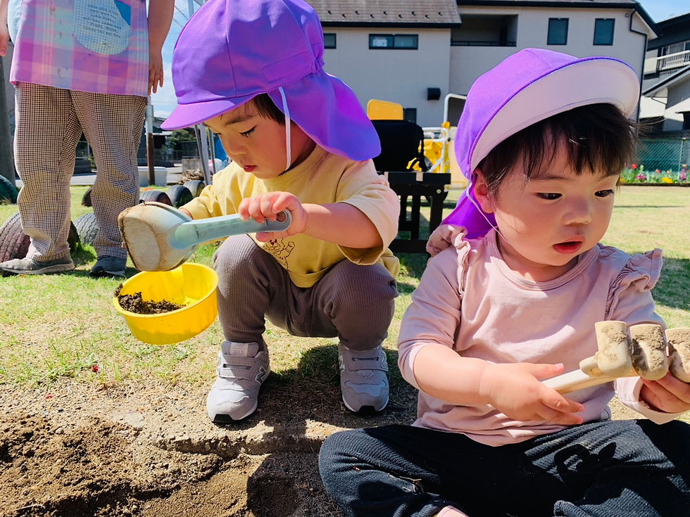 園庭で土に触れ合う園児2人