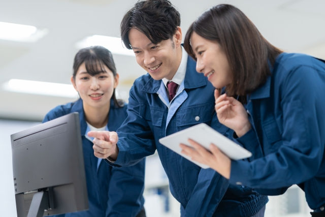 作業服の3人がパソコン画面を見て協力