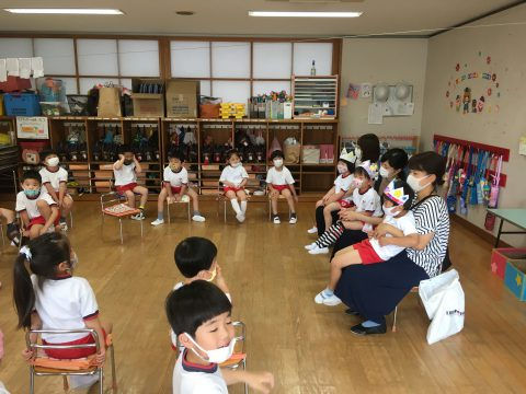 園児と先生が園舎で着席しています。年長組　参観日です。子供たちはマスクをしています。