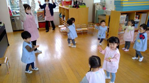 保育園の子供達と先生達。7月【年少】大掃除。笑顔で踊り、楽しんでいます。木製の床。