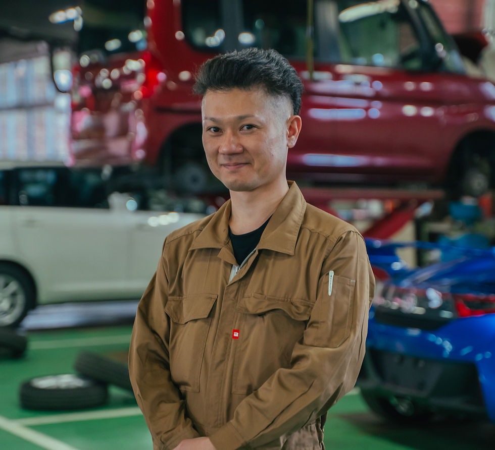 自動車整備工場で笑顔を見せる茶色のつなぎを着た男性社員