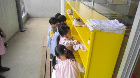 保育園の子供達が黄色い棚からタオルを取る 11月【年中】保育園の日常風景。