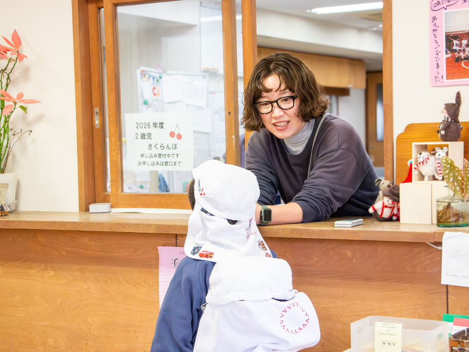 女性が白いお面をかぶった子供に笑顔を向けている