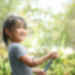 庭で遊ぶ女の子、笑顔で水鉄砲を噴射、楽しそうな様子です。