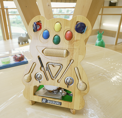 木製のクマの形をしたおもちゃ、カラフルなボタン、楽器が並んでいます。