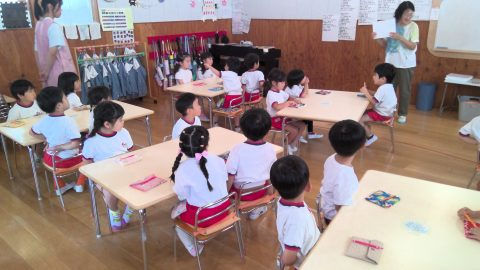保育園の教室で先生が何かを説明、子供達が聞いている様子。5月【年少】今週の様子です。