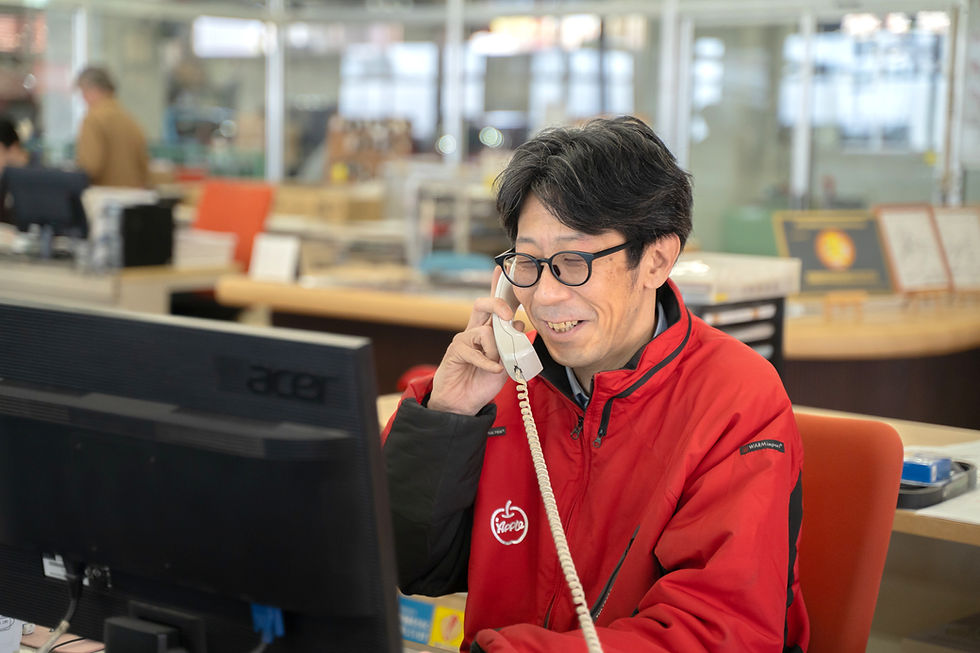 オフィスで電話対応をする赤いジャンパーの男性社員