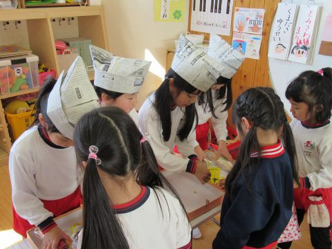 子供達が新聞紙の帽子を被って工作しています。楽しそう。おたのしみ会です。