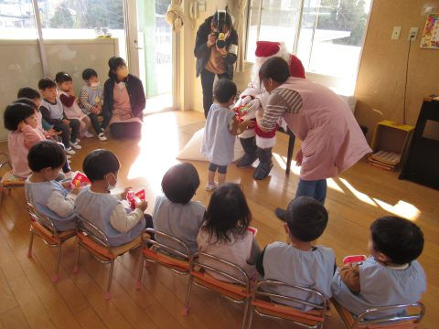 園児たちがサンタクロースからプレゼントを受け取っている様子。12月【年少】 クリスマス会。