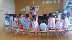 保育園の子供達が輪になって先生と練習しています。7月【年長】盆踊り練習、保育園での活動。