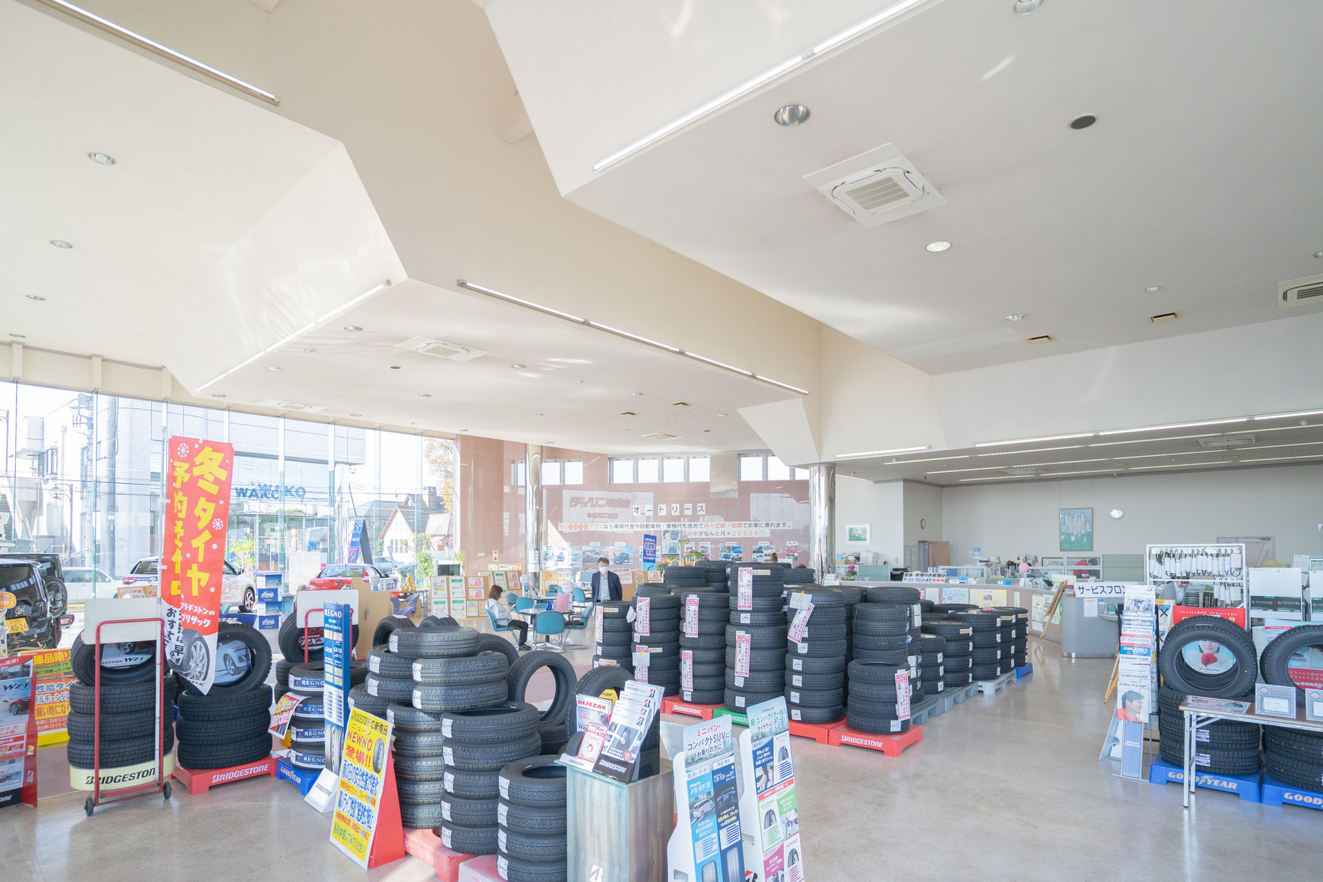 タイヤが山積みされた店内、様々な種類のタイヤが並ぶ。株）ジェイ・ピー オートギャラリーダイリン