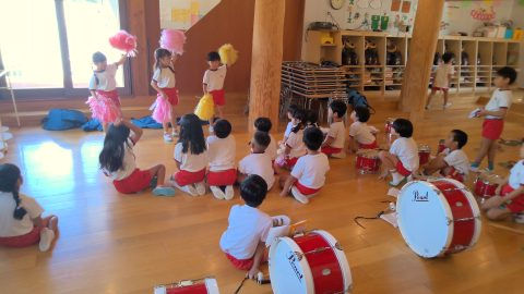 園児たちが踊る様子。赤いスカートと白いシャツを着て、5月【年少々】今週の様子。