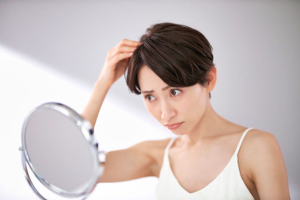 鏡を見て髪を心配する女性、薄毛を気にしている様子。