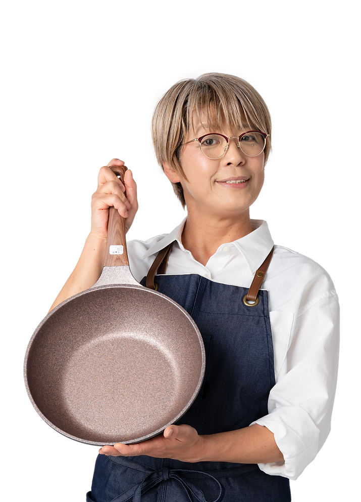 エプロン姿の女性がフライパンを持って笑顔