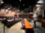 広い講堂で男性講師が大勢の学生に講演中。