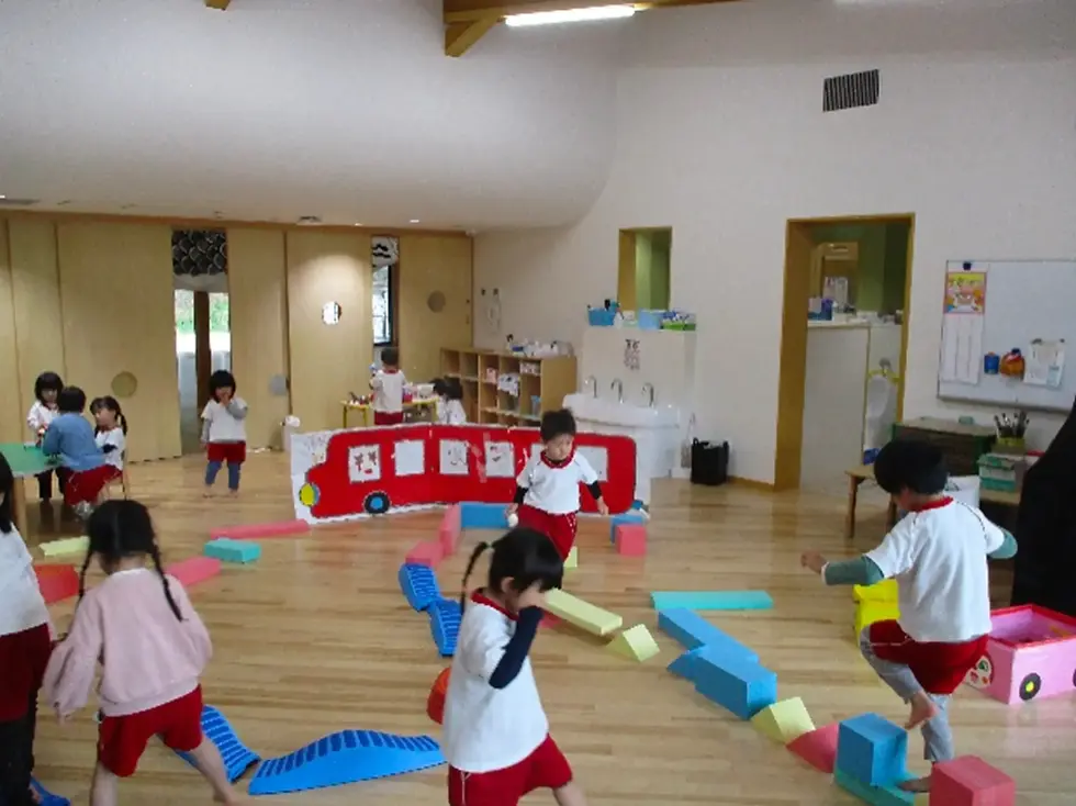 園児たちが室内でブロックやバスのおもちゃで遊ぶ。