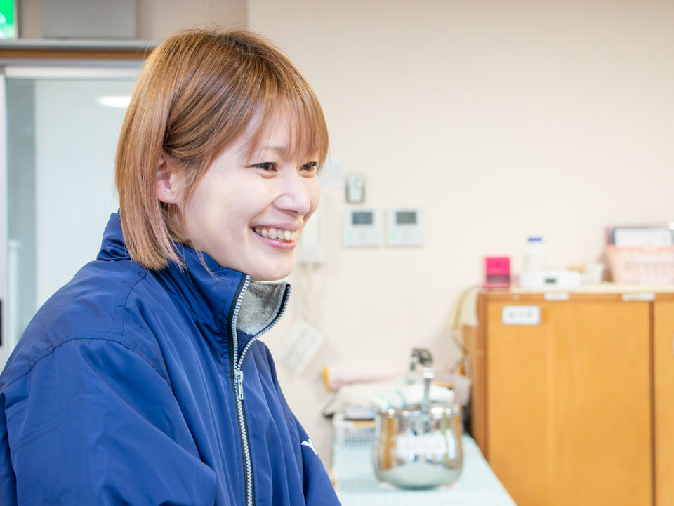 青い作業着を着て笑顔の女性