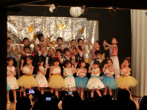 子供たちがステージで踊る様子。キラキラ光る飾りと年中組　お店屋さんごっこ。