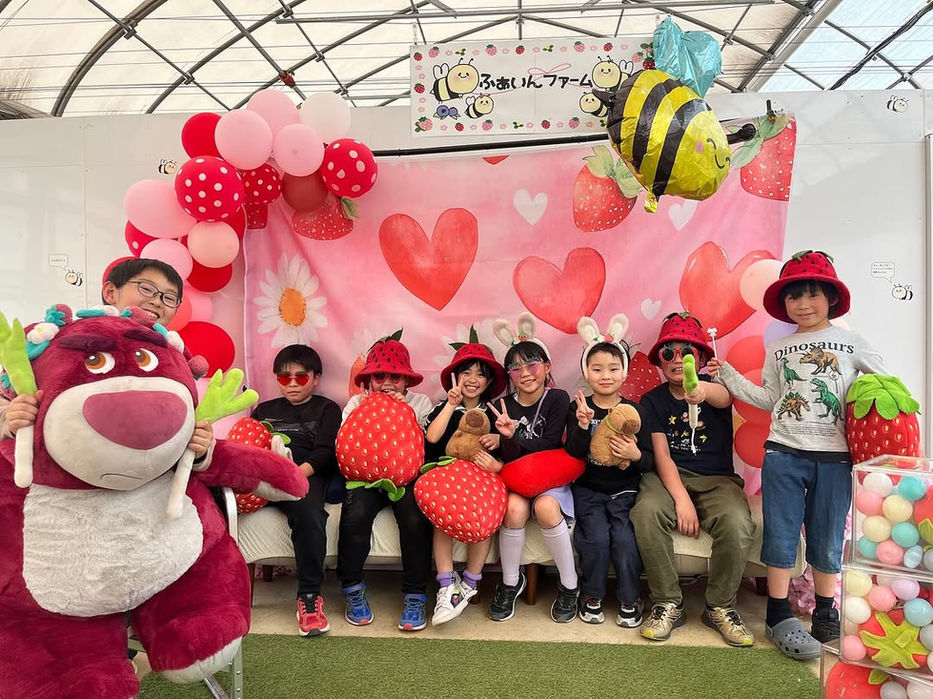子供たちがイチゴの飾り付けの前でポーズをとる写真