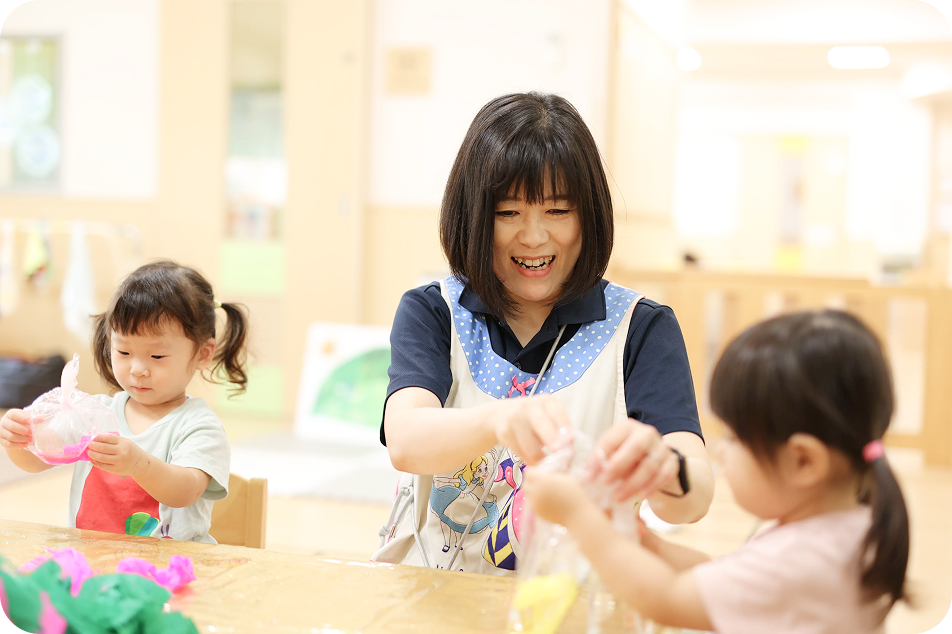 園児と一緒に工作を楽しむ笑顔の保育士