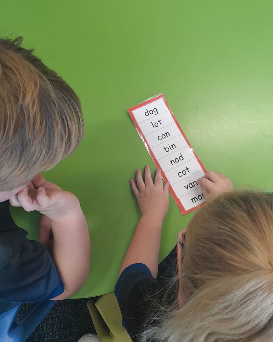 Students engaged in small-group literacy work, practicing spelling and phonics
