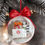 Thumbnail: A handmade clear ornament with miniature Red and white gift bags, faux snow, pink satin bow hanging on a Christmas