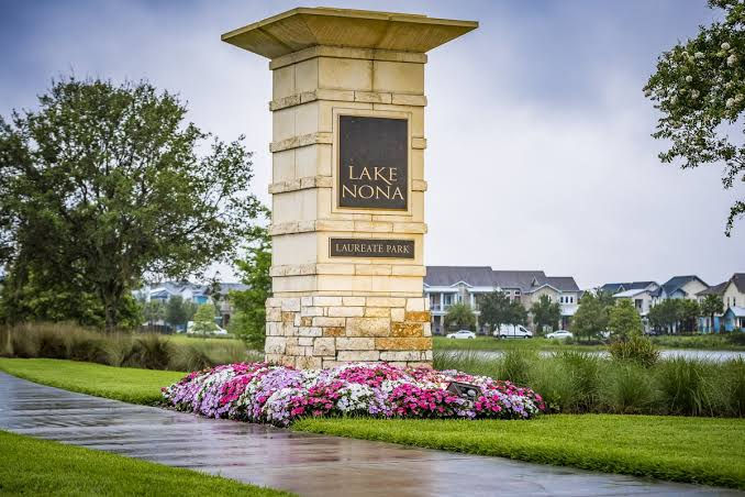 Lake Nona Laureate Park entrance monument surrounded by pink and white flowers, with homes in the background.