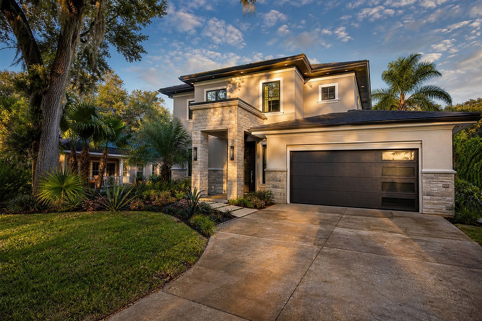 Modern two-story house with dark garage, palm trees, and landscaped yard glowing in warm sunset light under a blue sky