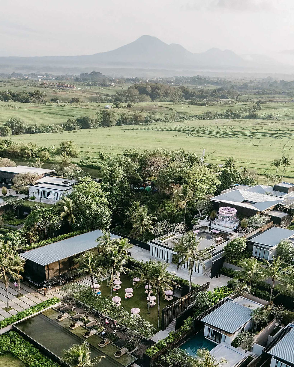 High aerial view of Cotta Lawn event setup framed by green rice paddies and volcanic mountains in Ta