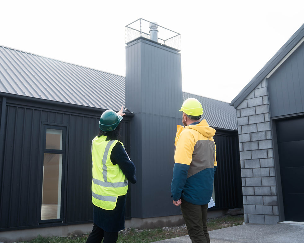 Two construction professionals inspecting a modern black-clad home chimney exterior, designed and built by Hedgley Corporation.