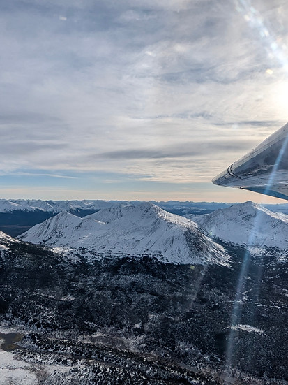 Float plane aerial image of snow capped mountains in September.