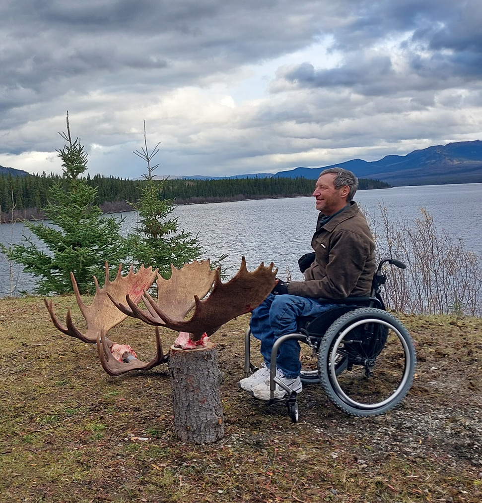 Man in wheelchair with Moose harvest back at base camp at Swan lake in Jennings River concession
