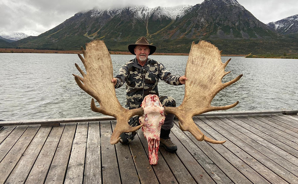 Man kneeling on dock wearing Kuiu hunting gear, with Canadian Moose antlers.
