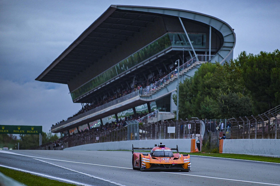 Orange race car speeds past a packed grandstand and Rolex sign on a wet track under a cloudy sky | Credit: Pete Phillips