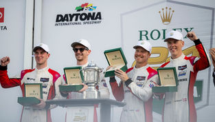 Four drivers of the LMP2 class-winning No.04 CrowdStrike Racing by APR, holding Rolex boxes and standing behind the trophy (L-R: Alex Quinn, Toby Sowery, George Kurtz and Malthe Jakobsen) | Credit: Fred Hardy Photography