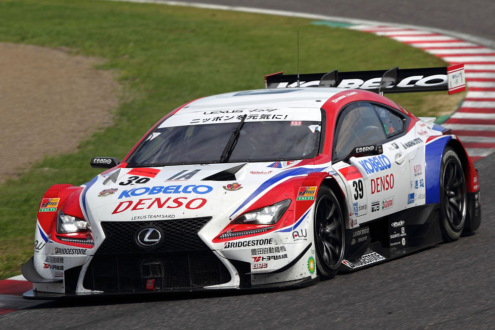 White, red, and blue Lexus race car with Kobelco and Denso logos speeds through a turn on a racetrack | Credit: Toyota Gazoo Racing