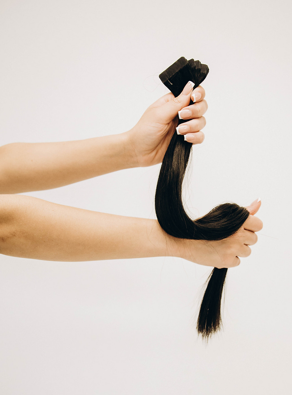 Model holding a bundle of tape-in hair extensions