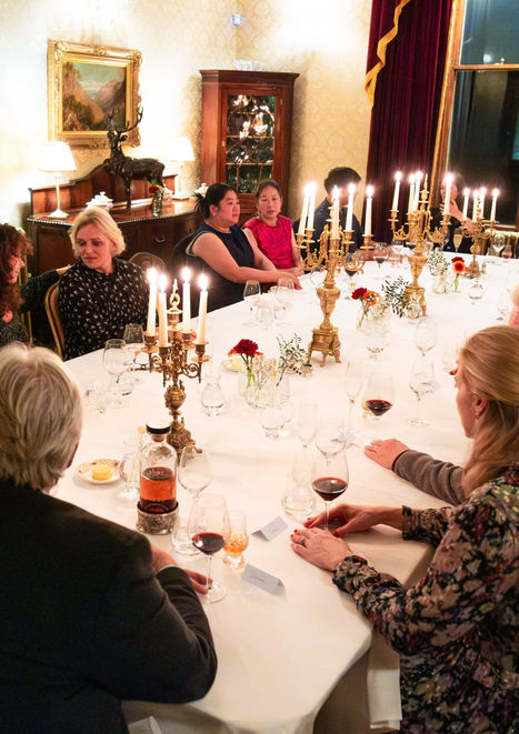 Guests enjoying a formal dinner with candlelight, wine glasses, and a long dining table