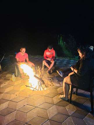 Backpackers sitting around a bonfire at night, sharing stories and laughter under the open sky.