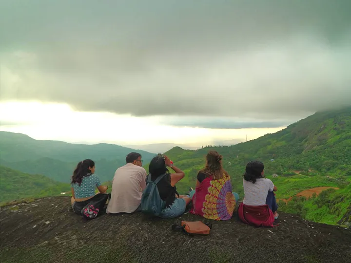 View from the Murugan Mala summit with the sky painted in hues of orange and pink during sunset.