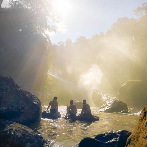 Guests dipping their feet in the clear waters beneath a secret waterfall, immersed in nature’s untouched beauty.