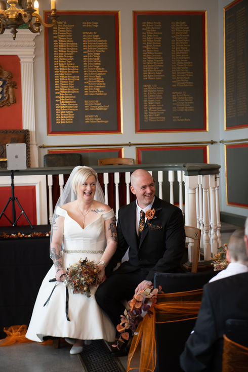 a bride and groom are sitting in front of a wall with a list of names on it